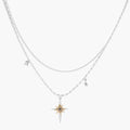 Two-layer silver-toned necklace with star charms and dagger pendant featuring golden sun motif on white background.