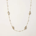 Long gold chain necklace with baroque pearls wrapped in leaf designs and small freshwater pearls spaced along the strand