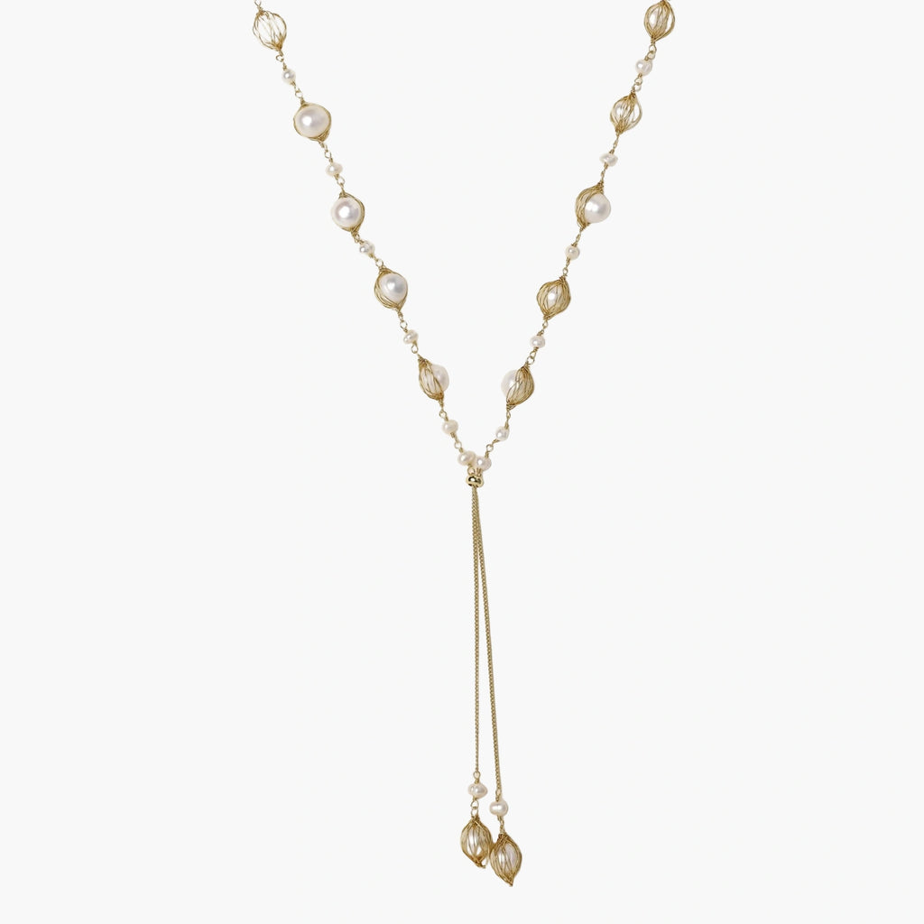 Adjustable gold lariat necklace with freshwater pearls nested in delicate cage settings and Y-shaped tassel drop