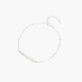 Delicate rhodium-plated silver chain bracelet with row of small baroque pearls centered on white background.