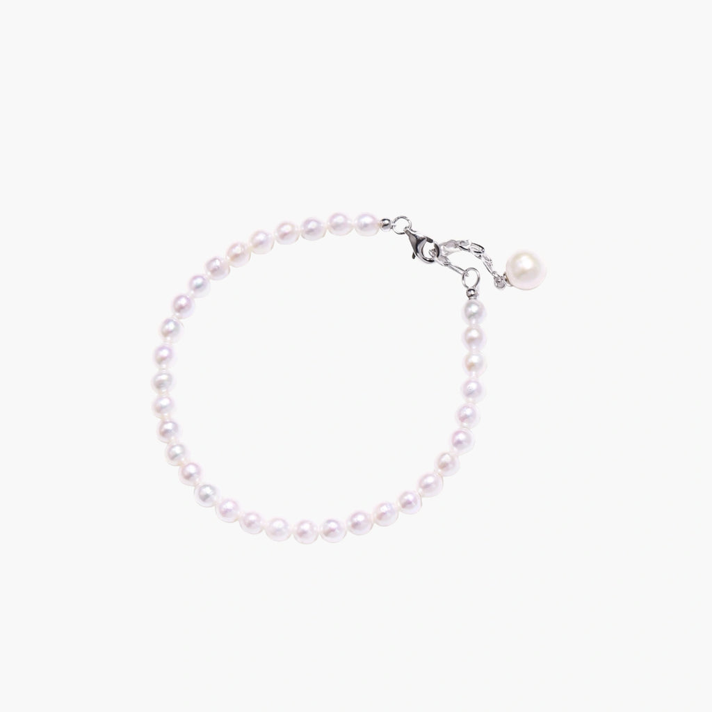 Adjustable bracelet featuring lustrous freshwater pearls with rhodium-plated sterling silver clasp on cream background.