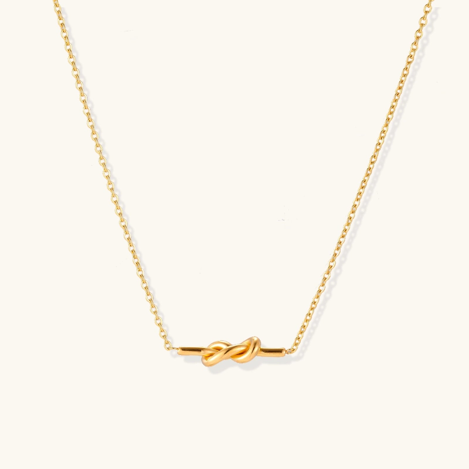 Dainty 18K gold plated necklace with infinity knot pendant on delicate chain against white background