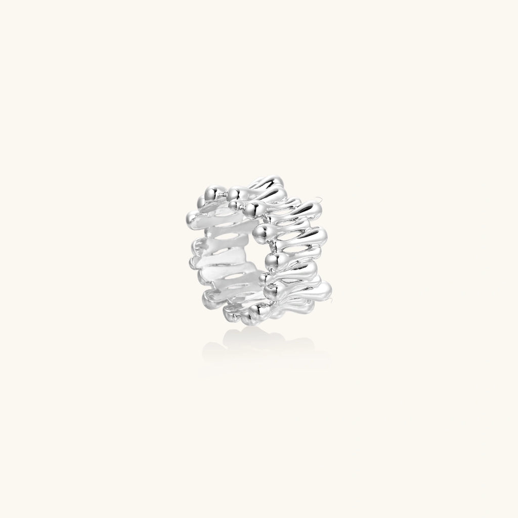 Wide band ring with sculptural wave ripples in polished white gold plated eco-brass on cream background