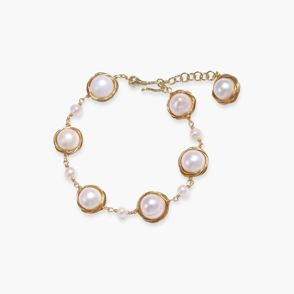 Gold wire-wrapped freshwater pearl bracelet with alternating pearl sizes on cream background, adjustable length
