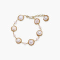 Gold wire-wrapped freshwater pearl bracelet with alternating pearl sizes on cream background, adjustable length