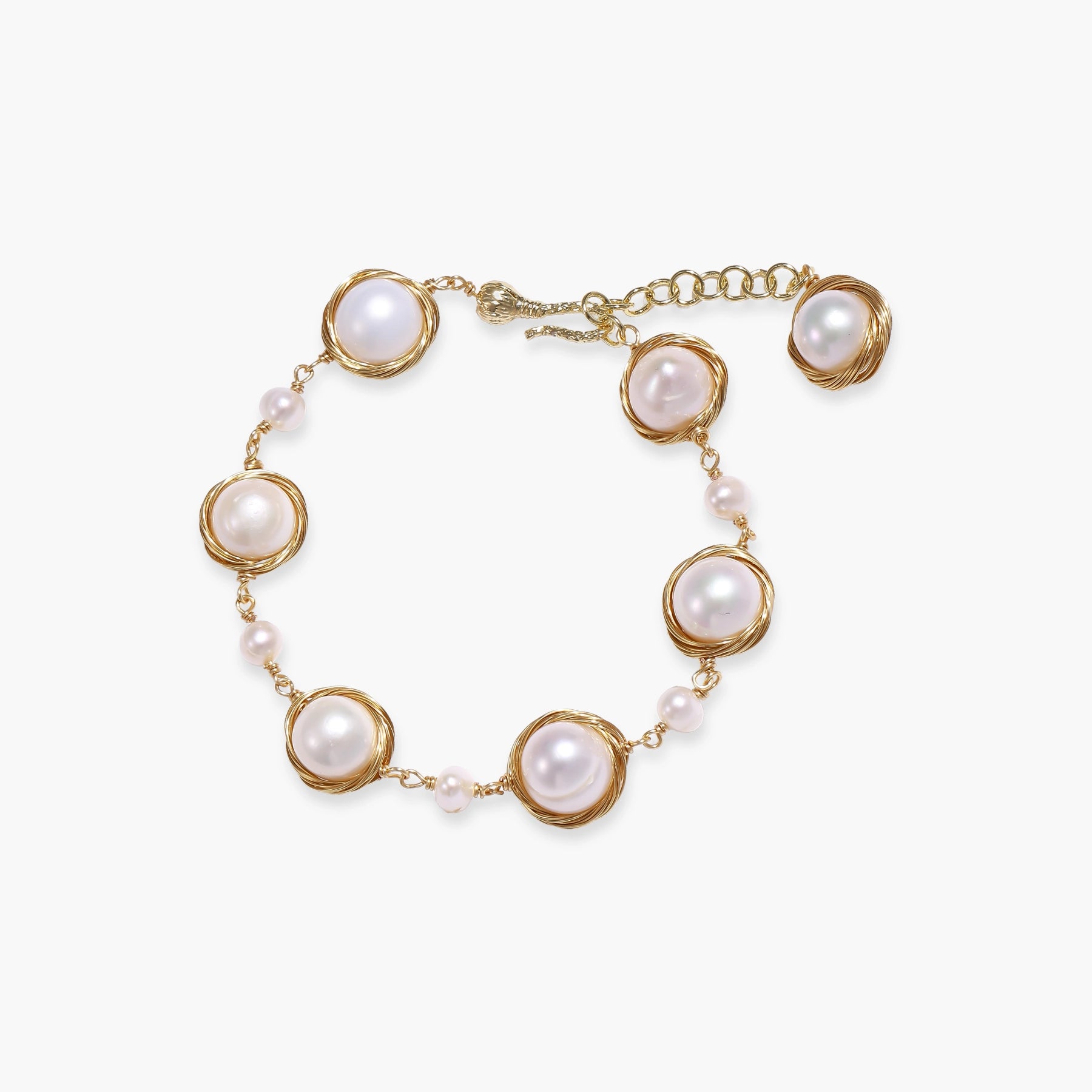 Gold wire-wrapped freshwater pearl bracelet with alternating pearl sizes on cream background, adjustable length